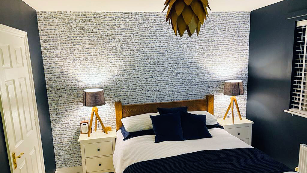 Bedroom with blue brick-effect feature wallpaper and navy walls