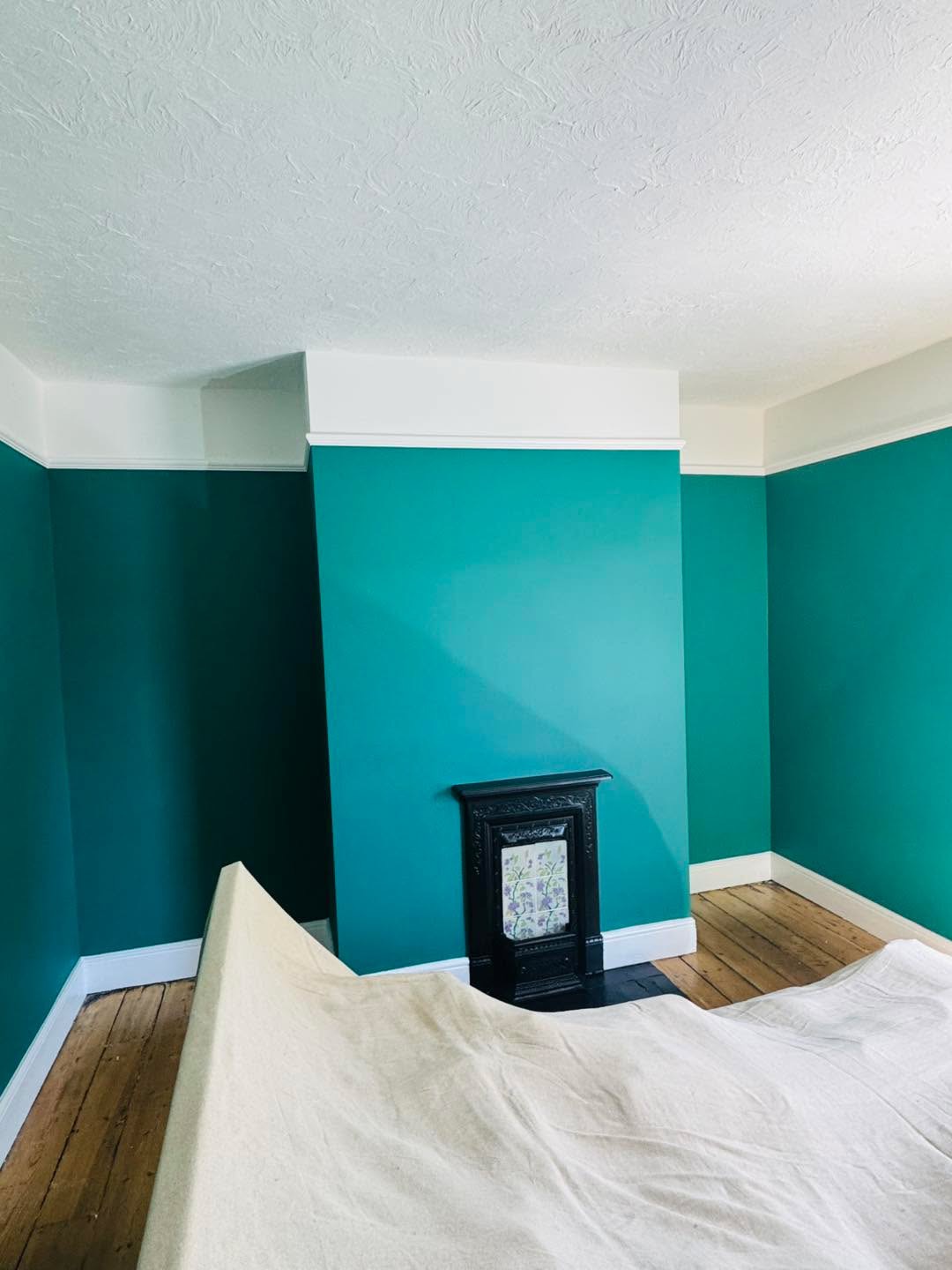 Teal room with white cornice and a cast-iron fireplace