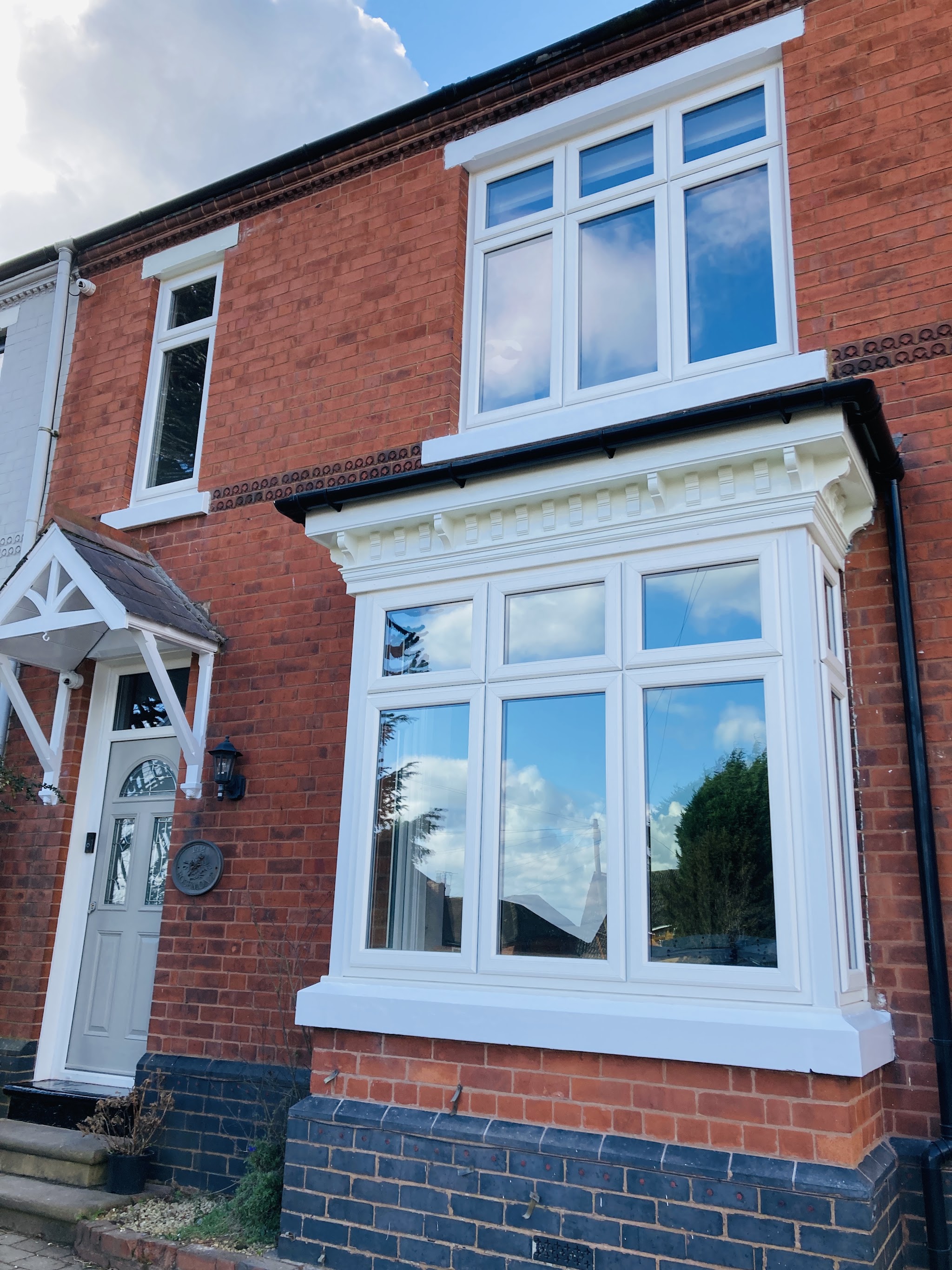 Red-brick Victorian terrace with freshly painted white bay window and fascia