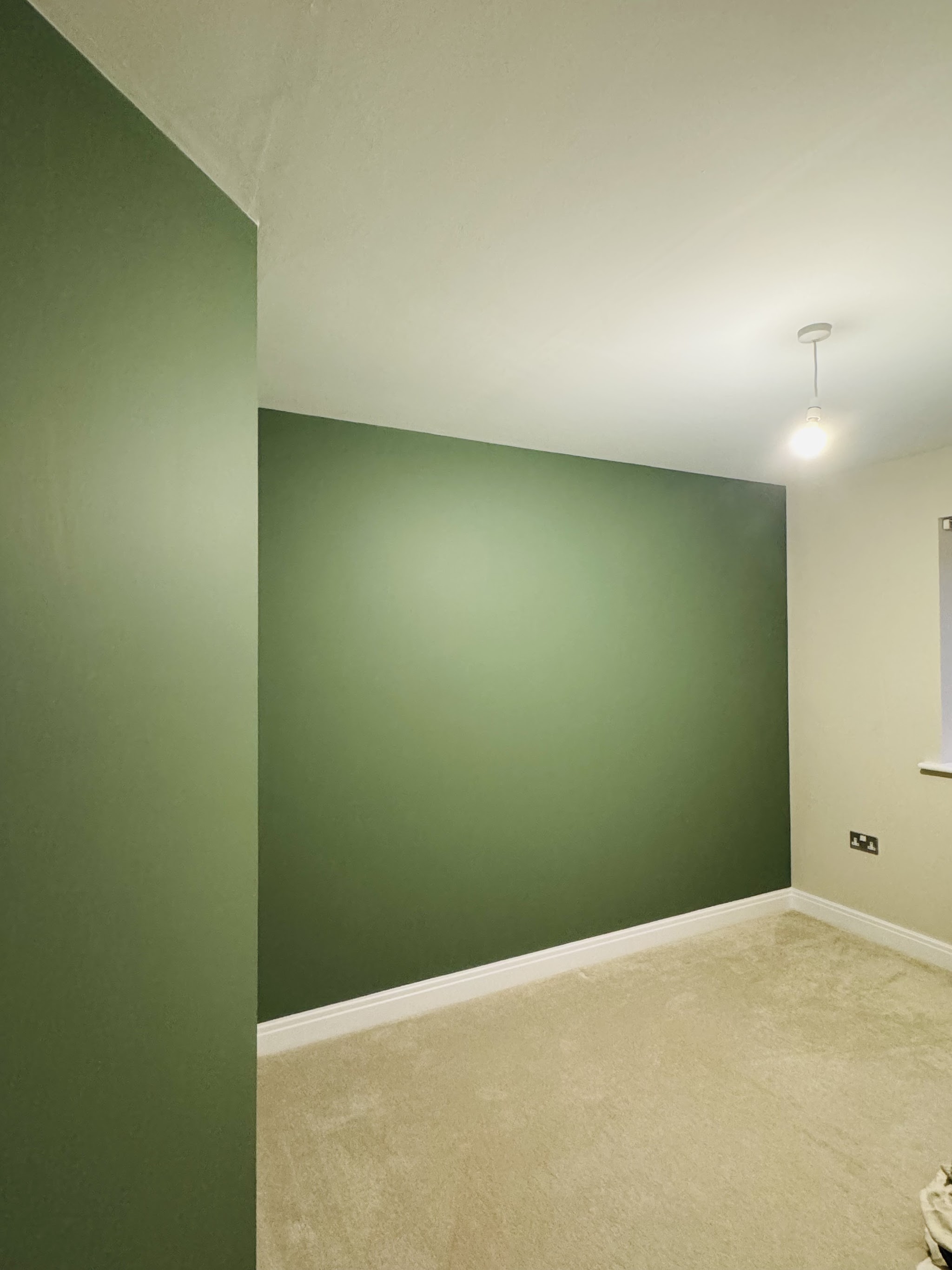 Bedroom painted in sage green with white skirting