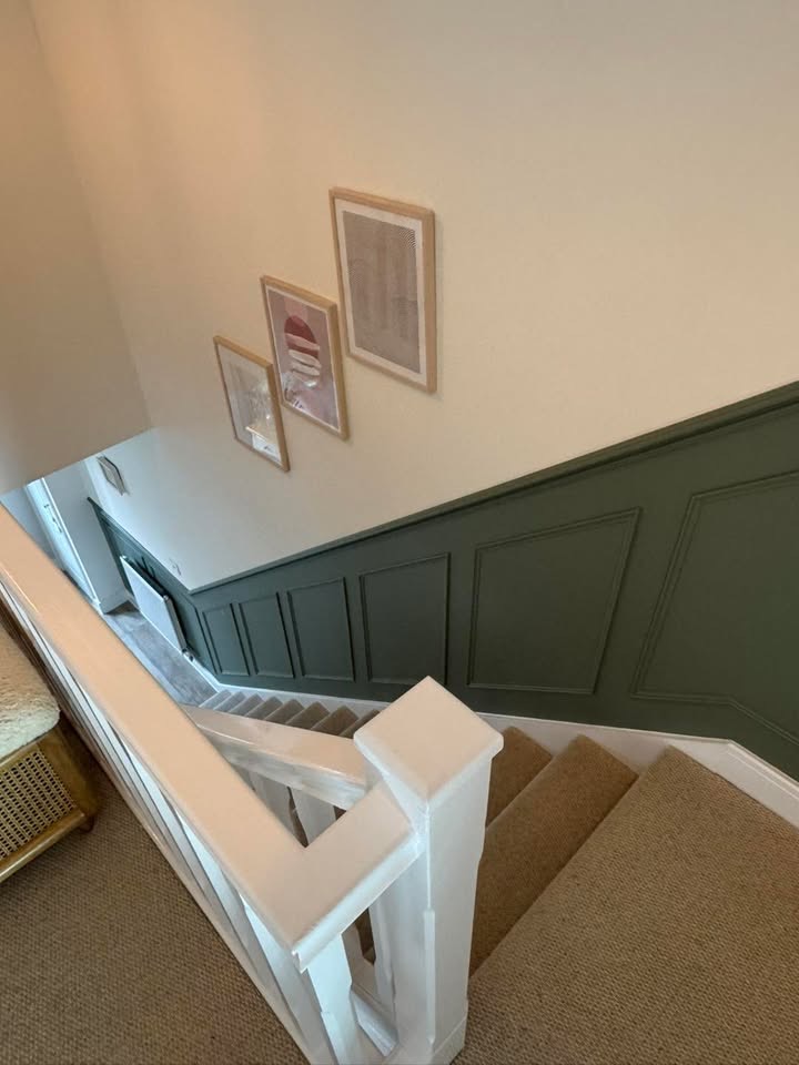 Stairwell with deep green panelling and a crisp white banister