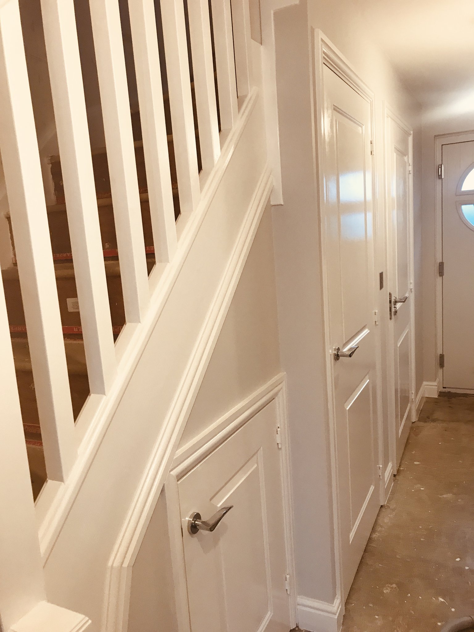 White hallway with panelled under-stair cupboard and spindles