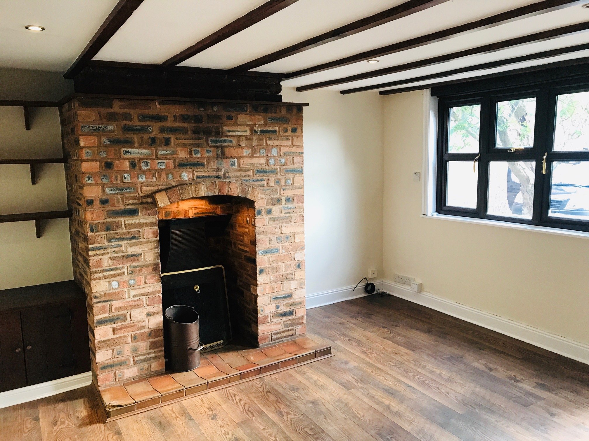 Beamed cottage room with a brick fireplace and cream walls