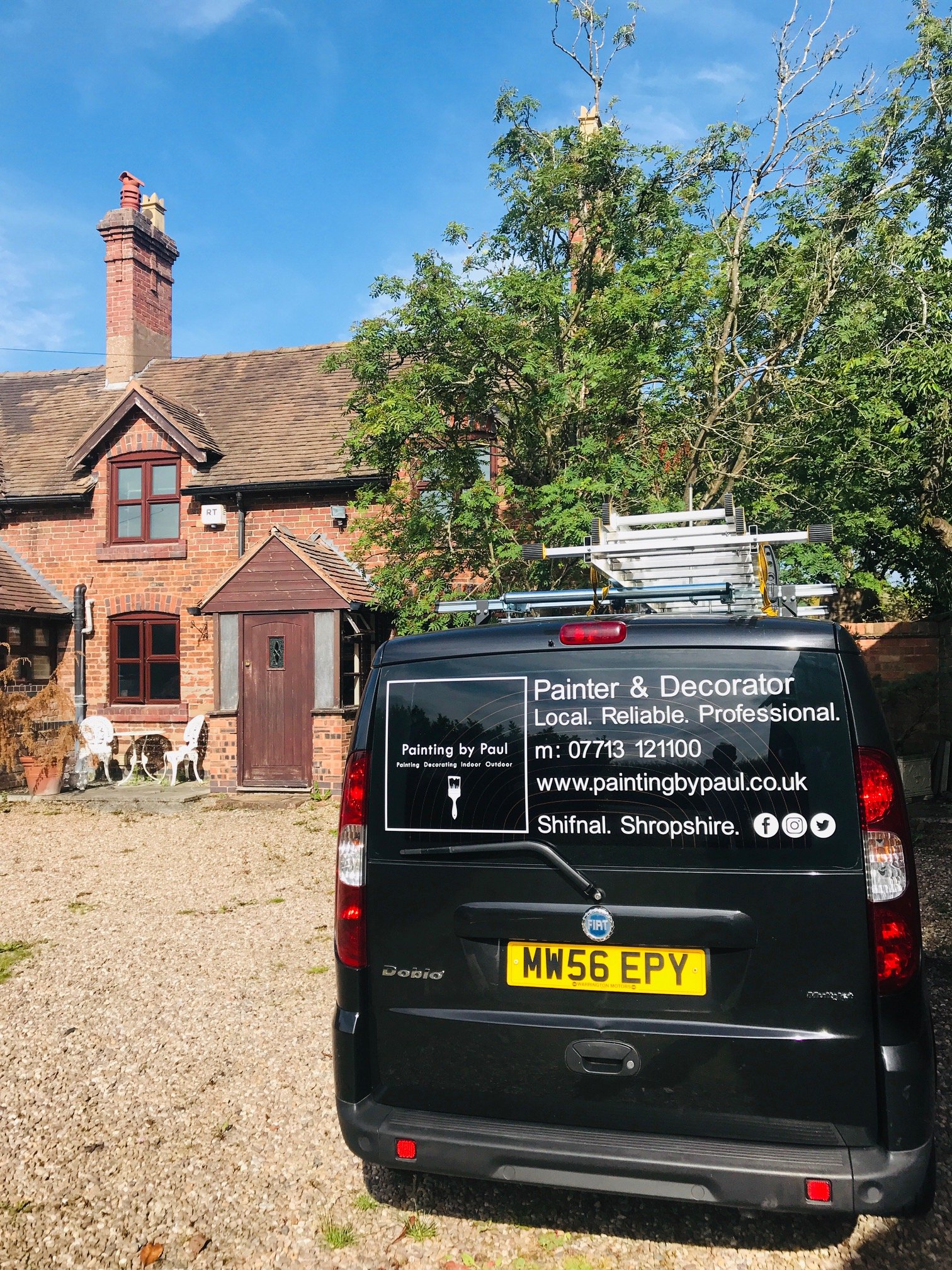 The Painting by Paul van parked outside a red-brick cottage