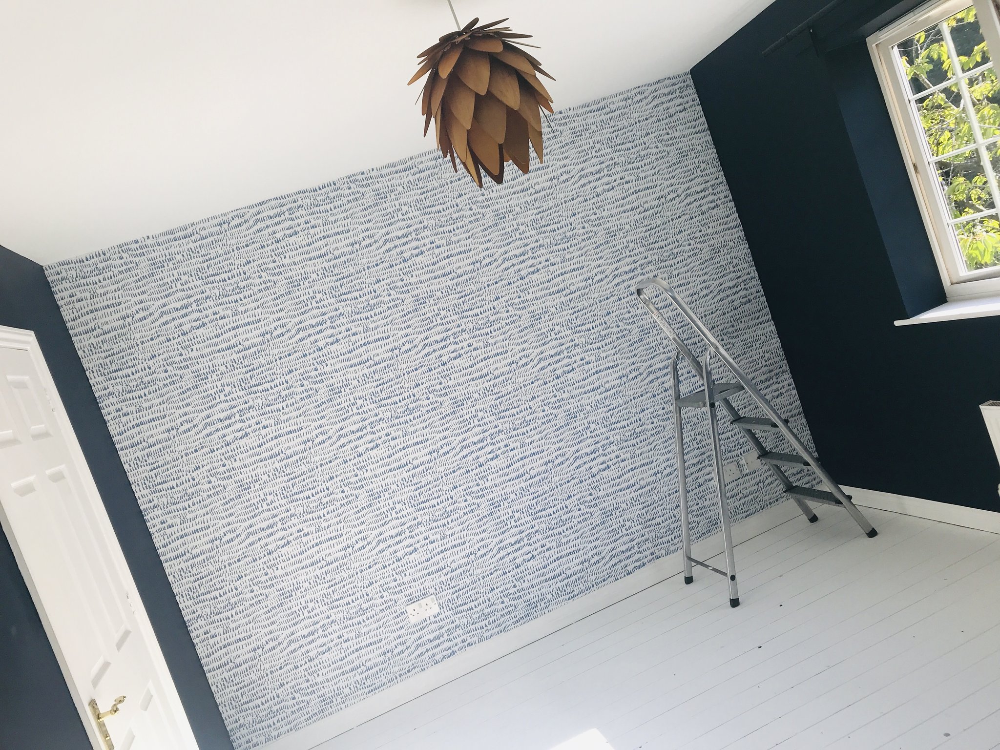 Feature wallpaper freshly hung beside a navy wall