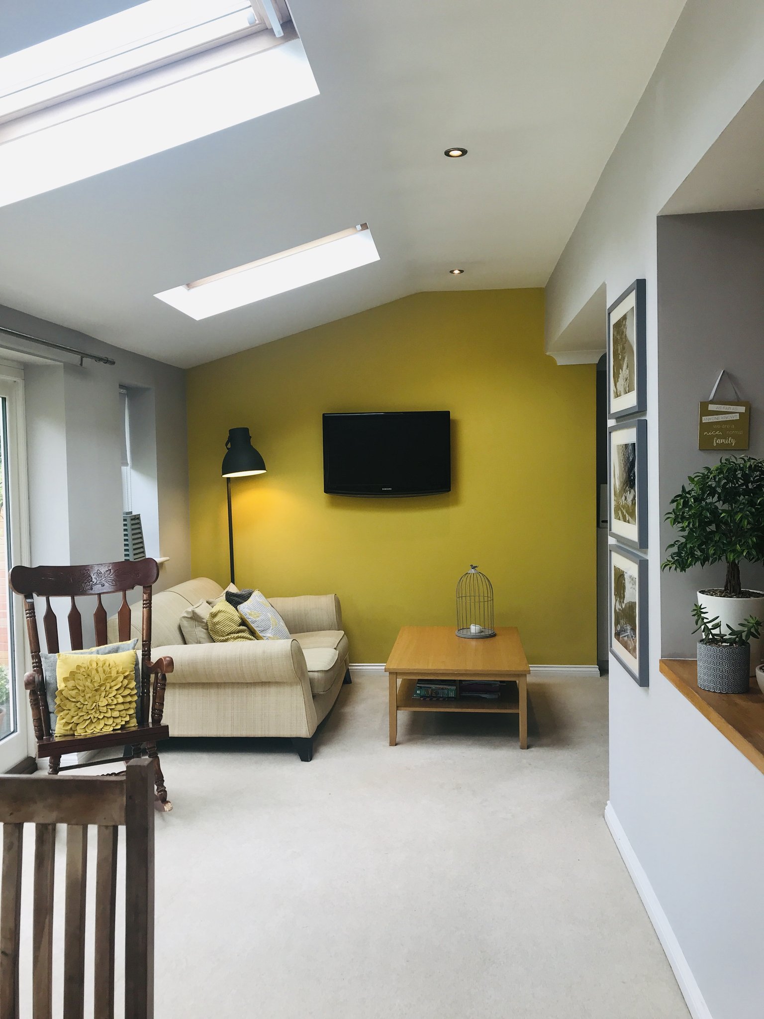 Living room with a mustard feature wall under skylights